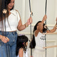 Woman and two young girls playing with a wooden swing and climbing toy indoors.